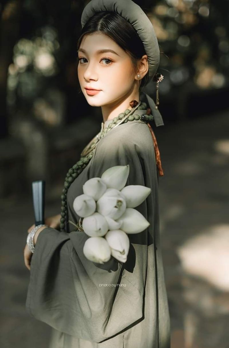 một cô gái mặc áo dài tay mang bó hoa sen